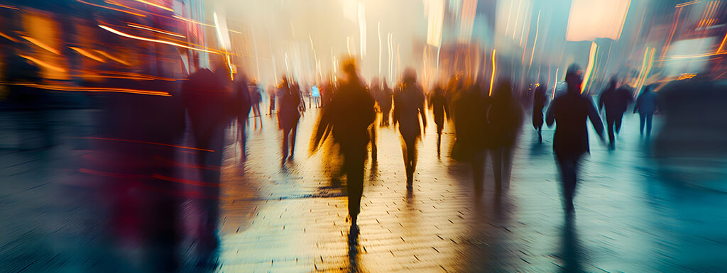 Blurred photo of people walking in a city square at sunset