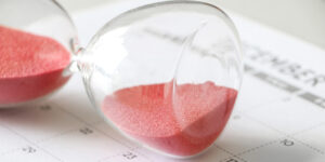 Hourglass with red sand on its side, on calendar, signifying pause, with the words A Short Pause of the Citizenship Clinic, along with the logo of Adoptees United