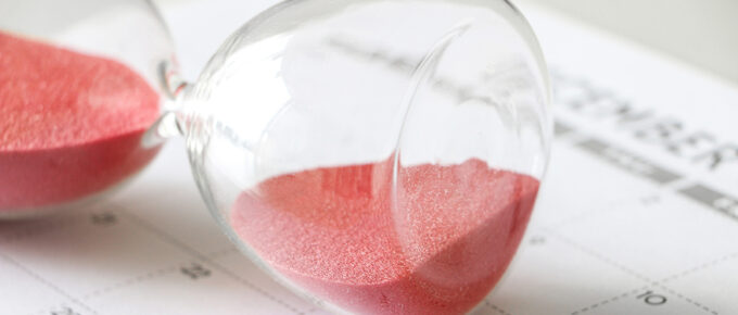 Hourglass with red sand on its side, on calendar, signifying pause, with the words A Short Pause of the Citizenship Clinic, along with the logo of Adoptees United